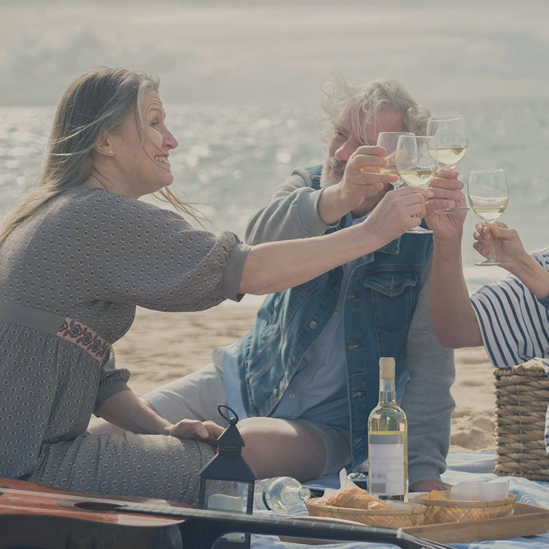 Older couple cheers with wine on the beach. west kelowna wine tour