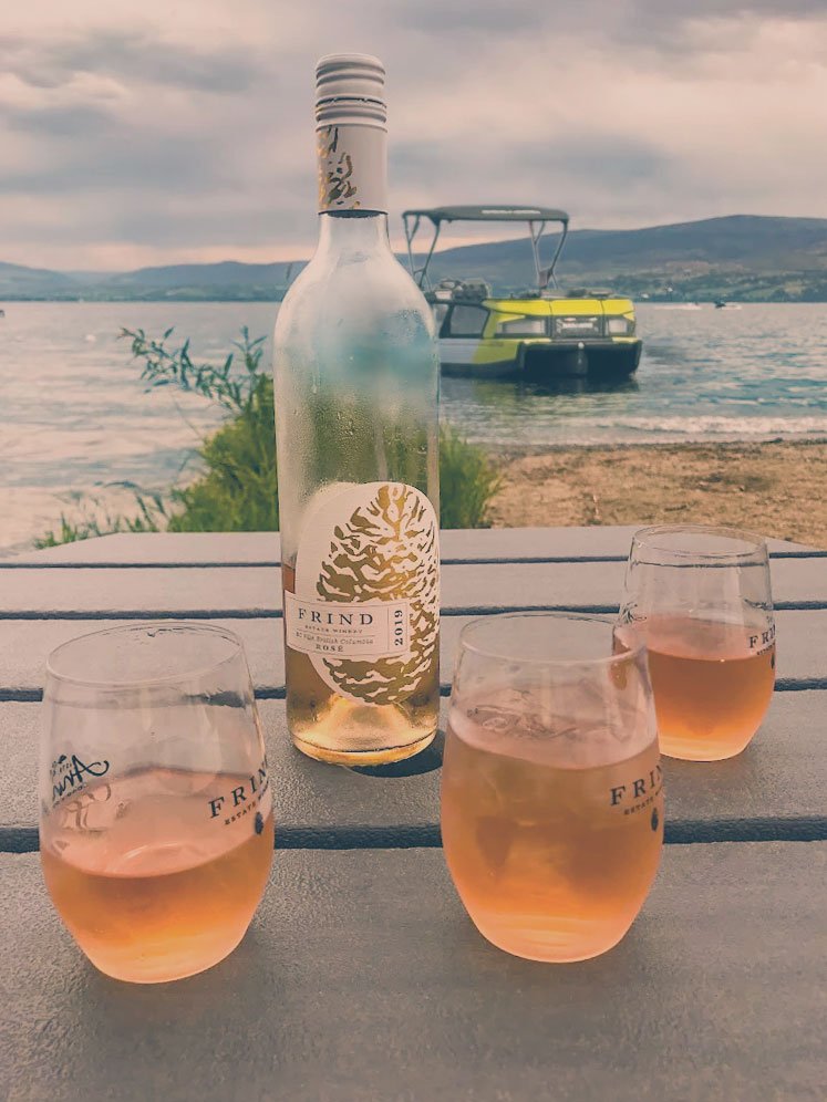 Frind_Boat_Wine_Vertical - okanara.com WIne bottle and glasses on a table at the beach at Frind Wine Estates.